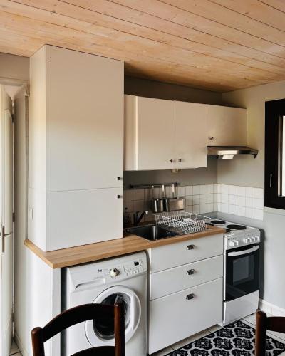 une cuisine avec des armoires blanches et une laveuse et une sécheuse dans l'établissement Gîte au bord du lac, à Vernet-la-Varenne