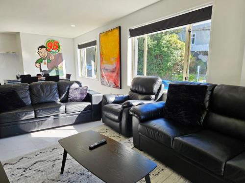 a living room with black leather couches and a table at Light & Airy Heart of Central Kelburn! in Wellington