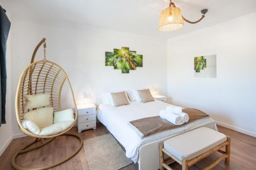 ein Schlafzimmer mit einem Schaukelbett und einem Stuhl in der Unterkunft Silver Coast Apartments Tulip in Atouguia da Baleia