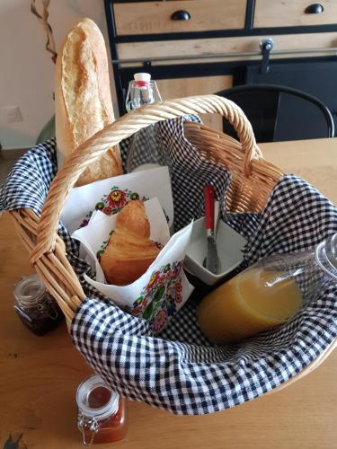 ein Korb mit Essen auf einem Tisch mit Brot in der Unterkunft studio au cœur de la vannerie in Fayl-Billot