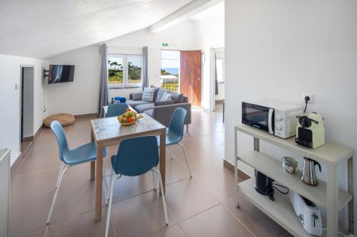 ein Wohnzimmer mit einem Tisch, Stühlen und einem Sofa in der Unterkunft Silvercoast Apartments - swimming pool & jacuzzi in Atouguia da Baleia