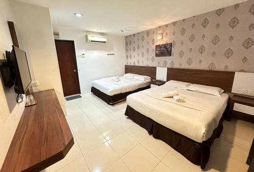 a hotel room with two beds and a television at Rainbow Hotel in Alor Setar