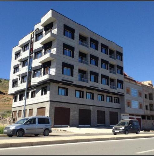 Andalouciene的住宿－Apartamentos Palace Rif Al Hoceima，两辆汽车停在一座大建筑前面