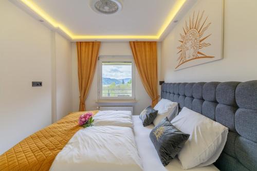 a bedroom with a bed with two pillows and a window at CT-GOLD Penthouse Bodensdorf Amatera privater Seezugang Hallenbad, Skiarena Gerlitzen in Bodensdorf