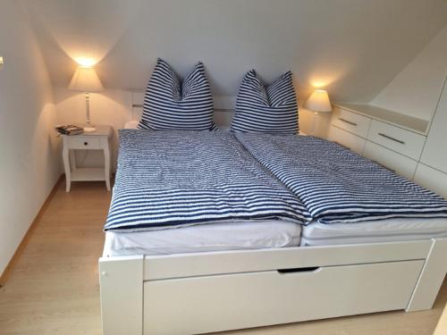 ein Bett mit blauen und weißen gestreiften Kissen darauf in der Unterkunft Ferienwohnung Südpol, Pellworm in Pellworm