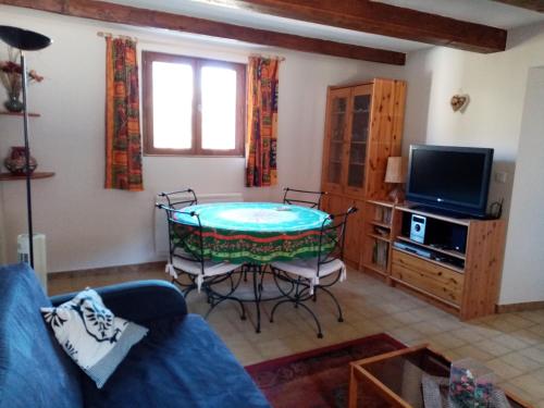 a living room with a table and a tv at La Quiétude in Entrevaux