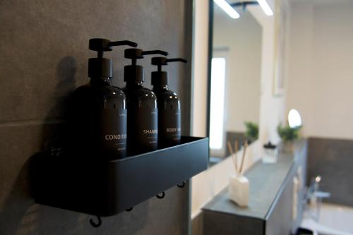 a bathroom with a shelf with four bottles on the wall at Fairmieten: Exklusive Suite I Terrasse I Parkplatz in Bielefeld