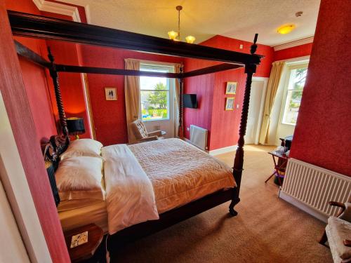 a bedroom with a canopy bed with red walls at The Pines Guest House in Elgin