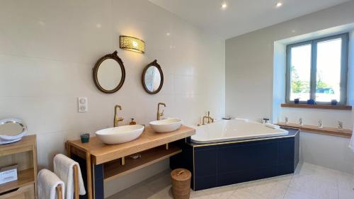 a bathroom with two sinks and a tub and mirror at La Demeure en Périgord in Anlhiac