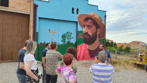 a group of people standing in front of a mural at Cal Robert in Penellas
