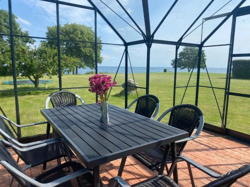 a black table with chairs and a vase with flowers on it at Sea view house - all year round in Frørup