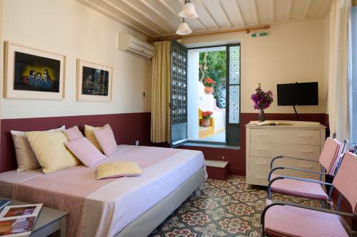 1 dormitorio con 1 cama, TV y ventana en Sto Roloi Island Houses en Poros