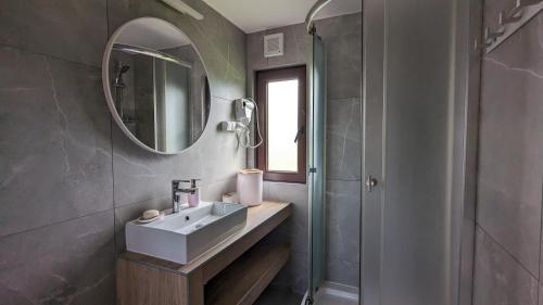 a bathroom with a sink and a mirror and a shower at Domki nad Soliną DAGA in Solina
