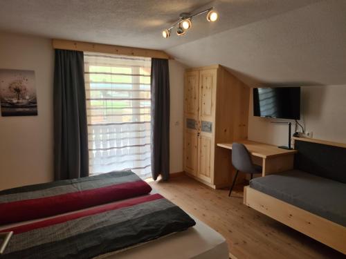 1 dormitorio con cama, escritorio y ventana en Ferienwohnung Auenheim, en Innervillgraten