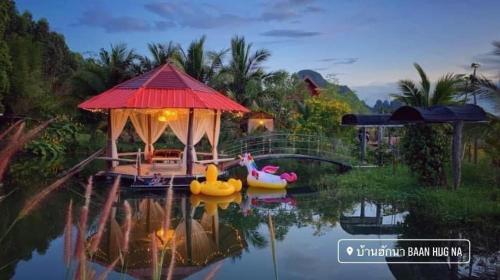Una casa con un estanque con dos patos de goma. en Baan Hug Na en Ban Khao Chakan
