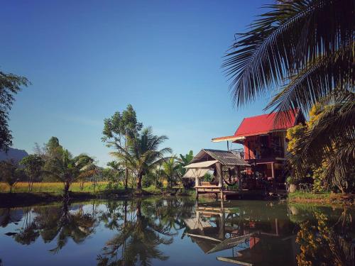 una casa junto a un cuerpo de agua con palmeras en Baan Hug Na en Ban Khao Chakan