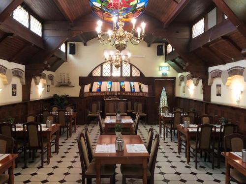 een restaurant met houten tafels en stoelen en een kroonluchter bij Hotel American in Venlo