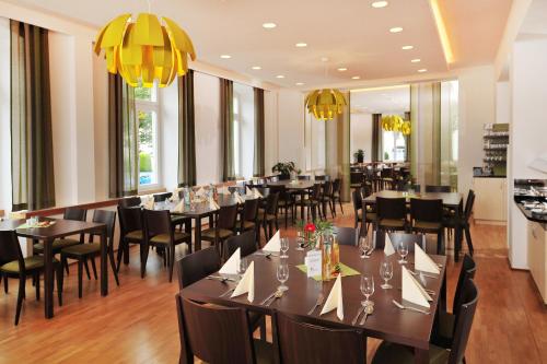 a dining room with tables and chairs and chandeliers at Bildungshaus St. Bernhard - Wohnen und Tagen in Rastatt