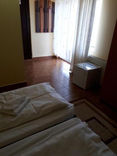 a bedroom with a white bed and a window at Pensiunea HARTTAS in Maliuc