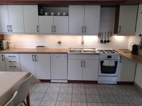 a kitchen with white cabinets and a sink and a stove at Apartament Kapi in Kalwaria Zebrzydowska