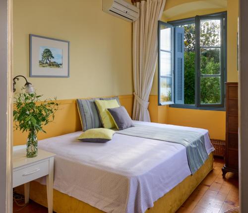 ein Schlafzimmer mit einem Bett und zwei Fenstern in der Unterkunft Sto Roloi Island Houses in Poros