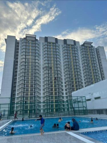 um grande edifício de apartamentos com pessoas numa piscina em d'zam residensi seri serindit em Bukit Baru