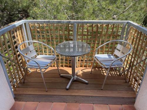 deux chaises et une table sur une terrasse en bois dans l'établissement L'Instant Plage - Vue Mer - Bord de Plage - La Capte - Côte d'Azur, à Hyères
