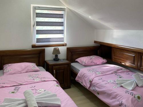 Duas camas num quarto com lençóis cor-de-rosa e uma janela. em Apartment LAKEVIEW em Plužine
