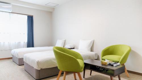 a hotel room with two beds and two chairs at Ayanishiki大阪西九条STAY in Osaka