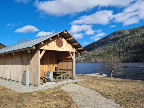 Cabaña de madera con mesa de picnic frente a un lago en Flott fjellhytte ned fantastisk utsikt., 