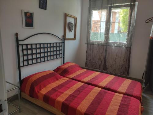 a bedroom with a bed with a striped comforter and a window at LA CASINA DE VEGA in Gijón