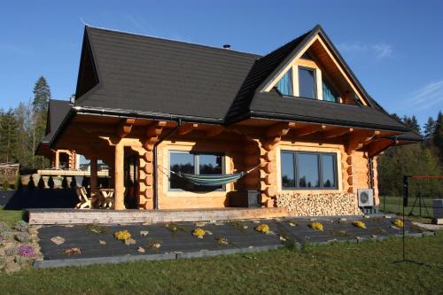 a log cabin with a hammock in front of it at Domek z balią - Dotyk Motyla in Łapsze Niżne