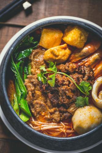 a bowl of food with noodles and meat and vegetables at Hotel Indigo Xiamen Harbour by IHG in Xiamen
