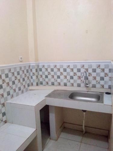 Łazienka z umywalką i ścianą wyłożoną kafelkami w obiekcie wisma wayang ajen syariah w mieście Cisalak