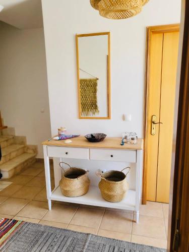a white console table with two baskets on it at Sand, Water & Sun House in Vila Nova De Cacela