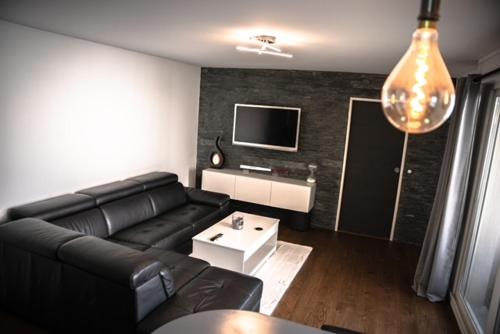 un salon avec un canapé noir et une télévision dans l'établissement F2 Vaires sur marne, à Vaires-sur-Marne