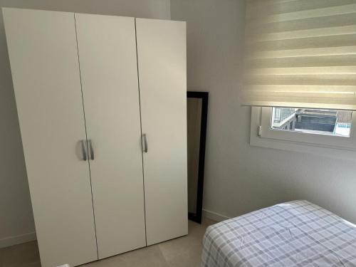 1 dormitorio con armarios blancos, 1 cama y ventana en Playa y confort en Segur de Calafell, en Segur de Calafell
