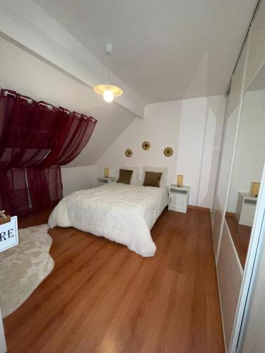 een slaapkamer met een groot wit bed en houten vloeren bij Appartement proche de Paris et l aeroport in Sevran