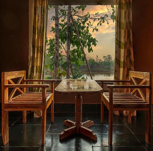 1 mesa y 2 sillas en una habitación con ventana en Jungleaashiyana, en Matkuli