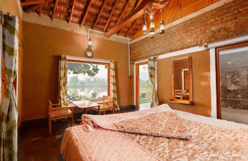 1 dormitorio con cama, mesa y ventana en Jungleaashiyana, en Matkuli