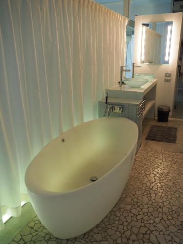 La salle de bains est pourvue d'une baignoire blanche et d'un lavabo. dans l'établissement La manufacture, à Antraigues-sur-Volane