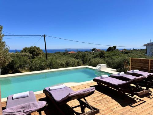 a swimming pool with two lounge chairs and a table at Astarte Villas - Stilvi 4 Bedroom Private Villa With Pool in Akrotiri