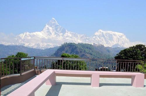 eine rosa Bank auf einem Balkon mit Bergblick in der Unterkunft Hotel Ezen in Pokhara