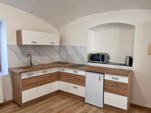 a small kitchen with white cabinets and a microwave at Ubytování v podzámčí in Úsov