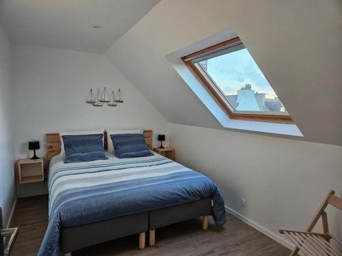 Schlafzimmer mit einem Bett mit blauer Bettwäsche und einem Fenster in der Unterkunft Kermorvan - pleine vue mer- parking et wifi - départ pour les îles in Le Conquet
