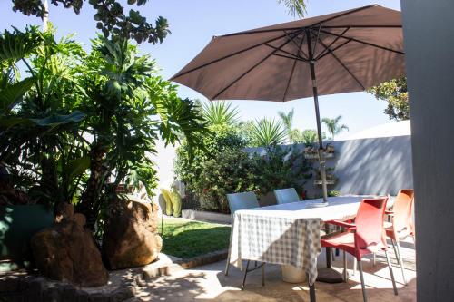 a table and chairs with an umbrella on a patio at Neapolitan Guesthouse in Alberton