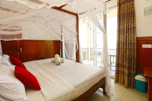 a bedroom with a canopy bed with a balcony at Srilak View Holiday Inn in Haputale
