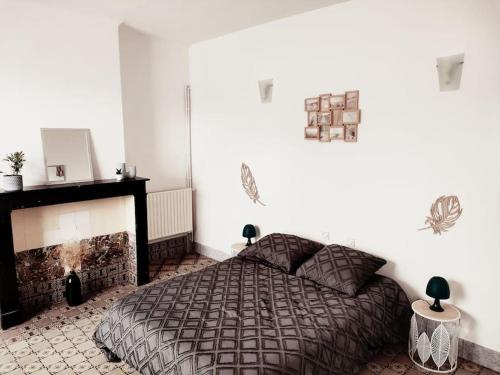 een slaapkamer met een bed en een open haard bij La ferme des sorciers in Agnez-lès-Duisans