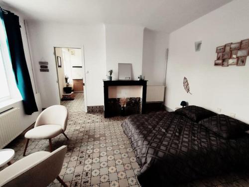 a bedroom with a bed and a chair and a fireplace at La ferme des sorciers in Agnez-lès-Duisans