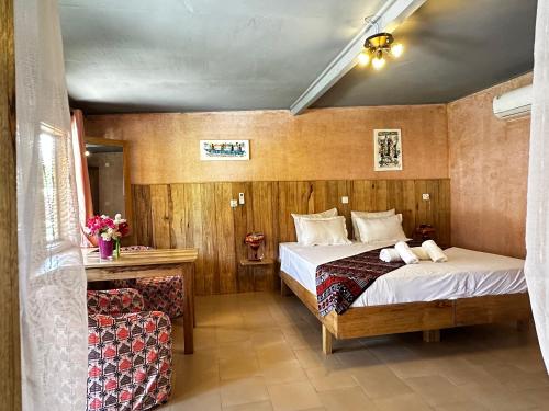 MbodièneにあるMariama Lodgeのベッドと椅子のあるホテルの部屋